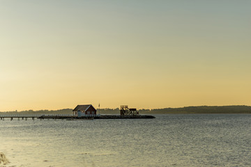 Obraz premium Einsames Haus am Wasser bei Sonnenaufgang