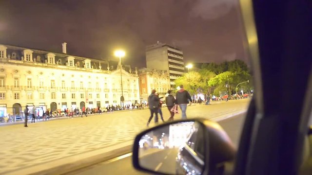 Driving through the liberty avenue at night with lots of people walking outside in Lisbon, Portugal