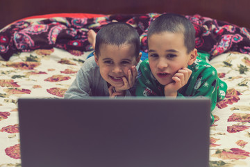 wo little brothers in pajamas are watching a cartoon on a laptop. Funny children enjoying cartoons on notebook, laptop or computer
