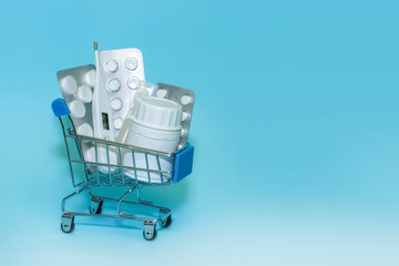 Shopping cart with pills on a blue background . The concept of the medicine of online shopping. Copy space for text