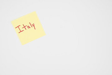 Italy in bold red lettering on a yellow sticky note with copyspace