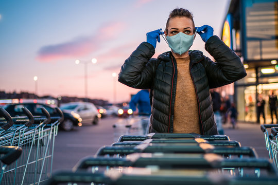 A woman wears medical protective gloves and a mask while shopping groceries.