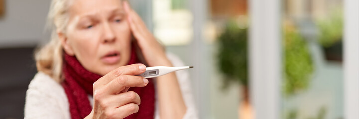 Woman looking at thermometer. Female hands holding a digital thermometer.