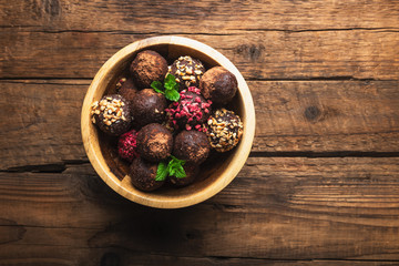 Various Homemade Raw Vegan Truffles or Energy Balls, such as Almond and Cacao, Dark Chocolate and Hazelnut Butter inside wooden Plate and Rustic Background