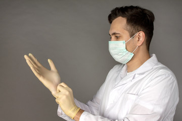 Portrait of a doctor in a medical gown putting on gloves before conducting tests for coronavirus