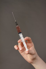 A man is holding a syringe with the contents of a vaccine against a new terrible virus-coronavirus