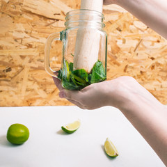 Girl squeezes juice from lime to make mojito. Goth a refreshing summer cocktail.