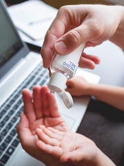 Self-isolation because of coronavirus outbreak. Man's hand with medical sanitizer gel for  skin sterilization. Father is remote working with his little son.