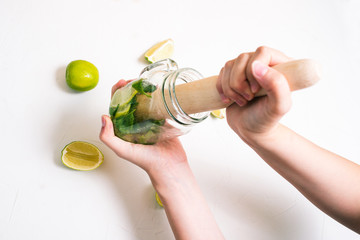 Cooking Mojito. Ingredients for making a summer refreshing cocktail. Mixing mint and lime leaves....