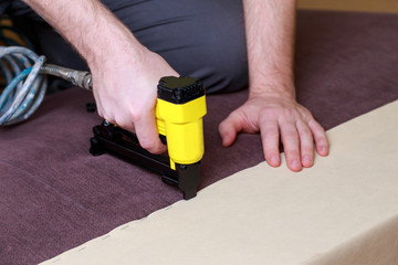 Man working with pneumatic stapler.