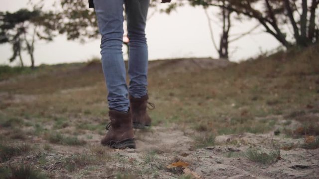 Boots of a young man hiking outdoor trough the sand and grass in slowmotion