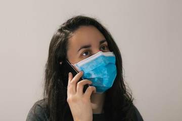 A young woman talks on the phone with a face mask on