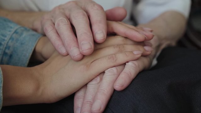 Close up of young female hands caress an elderly arms and rearrange hand on hand