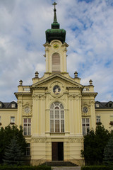 Fototapeta na wymiar Facade of a catholic temple with a tower clock against a cloudy sky