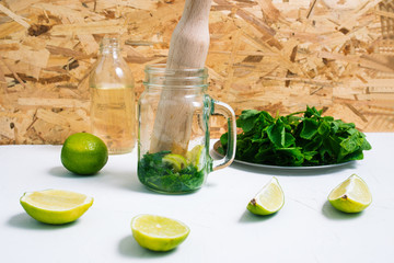Glass cocktail jar with mixed mint and lime. The process of making mojito. Summer fruit drink.