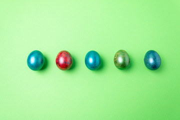 Easter card concept. colored easter eggs in a row on a light green background