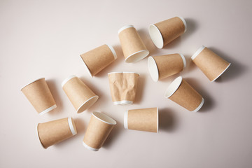 paper cups with rumpled cup in middle isolated on brown background