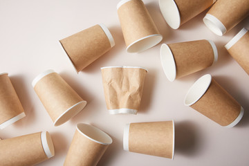 paper cups with rumpled cup in middle isolated on brown background