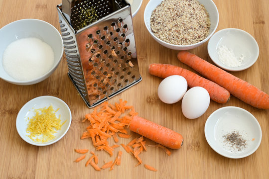Grated carrots, ground almonds, eggs and spices, baking ingredients on a wooden kitchen board for an Easter carrot cake