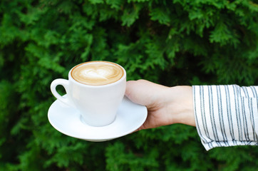 Female hand holds a cup of coffee.