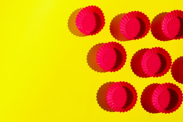 Red silicone cookie cutters on a yellow background. Abstract colorful backdrop, horizontal view, copy space for text. 