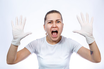 Girl paramedic puts on white medical gloves on hands. Protection against germs and viruses. She is in a white T-shirt on a white background.