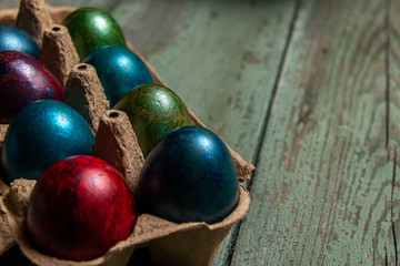 Colorful easter eggs in an egg palette and on an old wooden table. Easter concept.