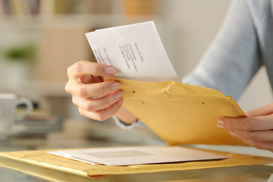 Woman Hands Opening A Padded Envelope On A Desk