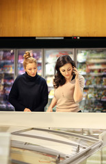 Two women choosing frozen food from a supermarket freezer	