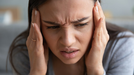 Close up of sick young woman touch massage temples suffer from headache or migraine, ill millennial...