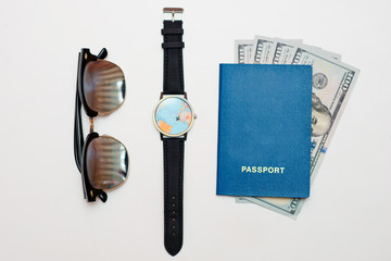 Neatly laid out passport with cash, glasses, and wristwatch on a white background. Top view. Travel concept, space for text