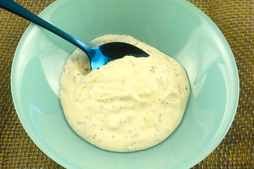 Fresh homemade dill crema sauce with blue spoon and bowl
