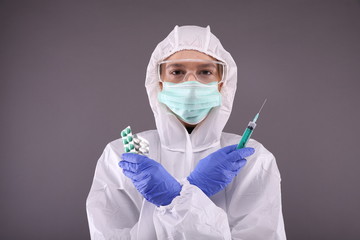 Woman in protective costume, mask with pills in hands