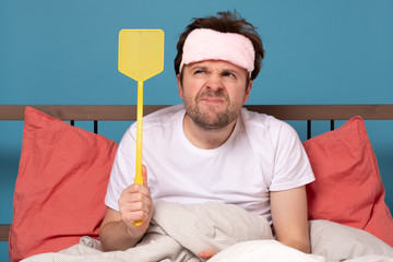 man holding a fly swatter wanting to kill annoying mosquito