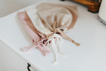 Three small fruit and vegetable reusable bags for eco friendly shopping on white modern kitchen. Beige, pink and white handmade bags