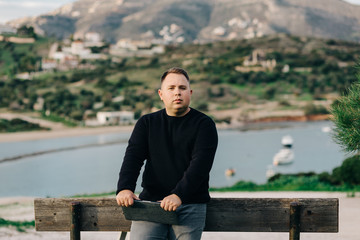Obraz premium Freelancer guy stands near the bench with a laptop in his hands and looks at the camera