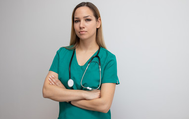 Confident nurse standing arms crossed. Confident young woman doctor. Intern nurse. Young pretty woman in green clothes with a stethoscope posing 