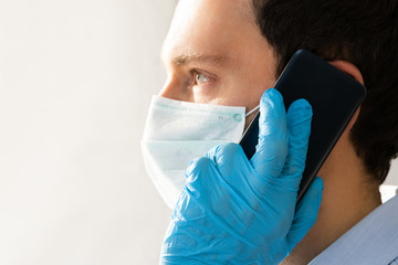 Man In Mask And Gloves Using Mobile Phone