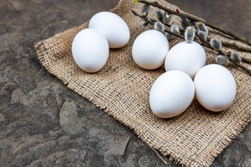 Fresh organic farm eggs lie on burlap, on a stone slab, close-up, selective frus, shallow depth of field. Concept, healthy food, spring religious holidays.