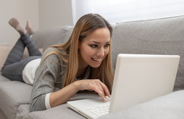 Woman using tablet on a home couch. Woman surfing on line or working from home concept