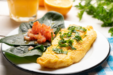 French omelette with tomato and spinach on white background