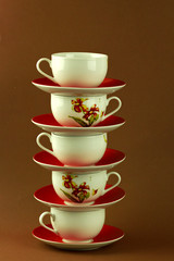 many cups and saucers stand on top of each other, a high tower of kitchen utensils, tea and coffee