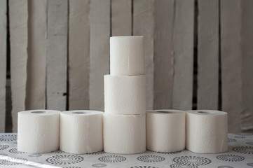 Rolls of white toilet paper on the background of hanging gray toilet paper tapes. Coronovirus...