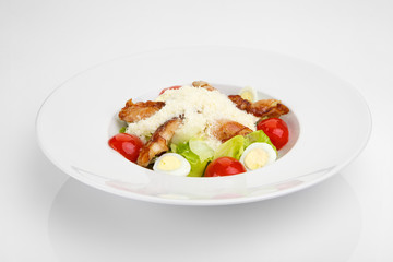 Salad with fresh vegetables, eggs and chicken on white plate
