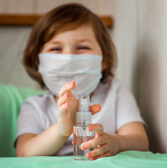 a little girl, in a medical mask , with a dysenfector in her hands, is being quarantined at home because of COVID-19