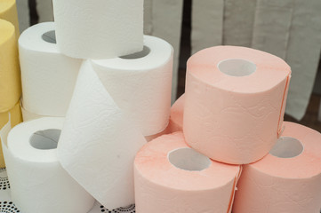 Rolls of white, yellow, red and green toilet paper on the background of hanging gray toilet paper tapes. Coronovirus Currency