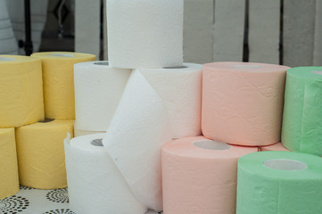 Rolls of white, yellow, red and green toilet paper on the background of hanging gray toilet paper tapes. Coronovirus Currency
