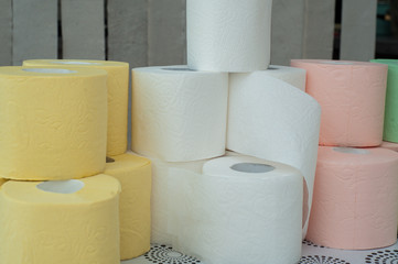 Rolls of white, yellow, red and green toilet paper on the background of hanging gray toilet paper tapes. Coronovirus Currency