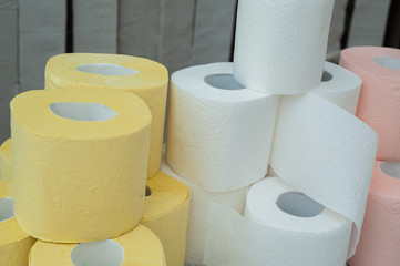 Rolls of white, yellow, red and green toilet paper on the background of hanging gray toilet paper tapes. Coronovirus Currency