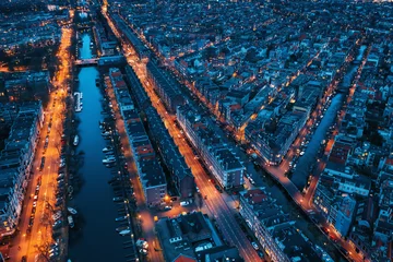 Poster Mooie nachtelijke luchtfoto van het centrum van Amsterdam van bovenaf met veel smalle grachten, verlichte straten en oude historische huizen, drone foto. © DedMityay